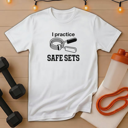 White t-shirt with "I practice SAFE SETS" text and weightlifting accessories.