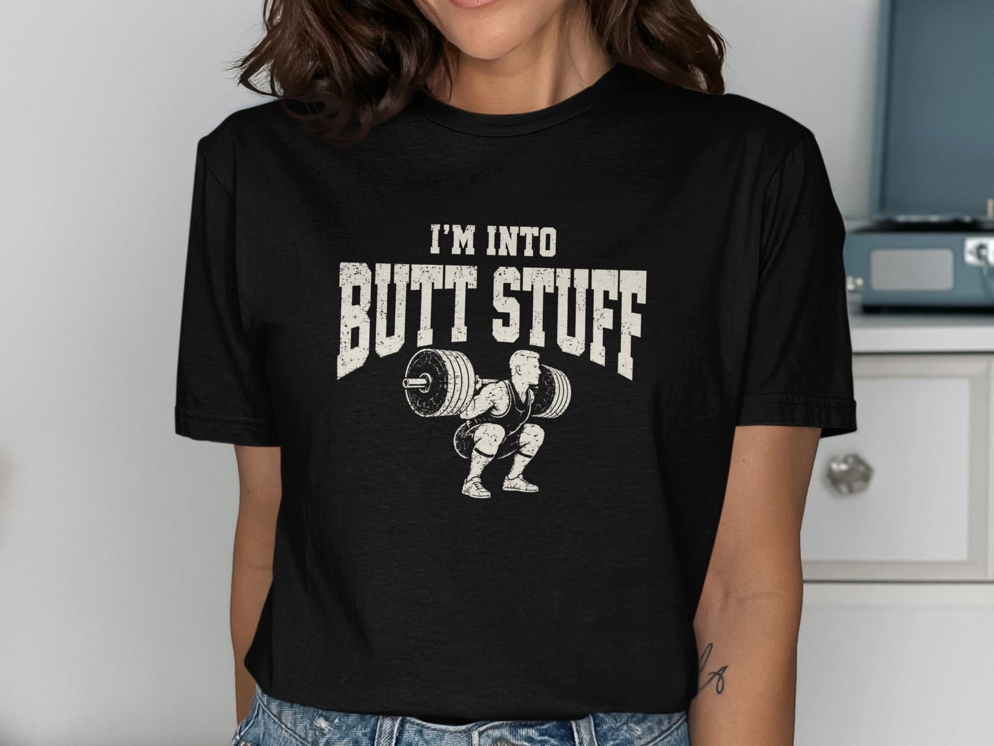 Black t-shirt with distressed graphic of weightlifter squatting and text "I'M INTO BUTT STUFF."