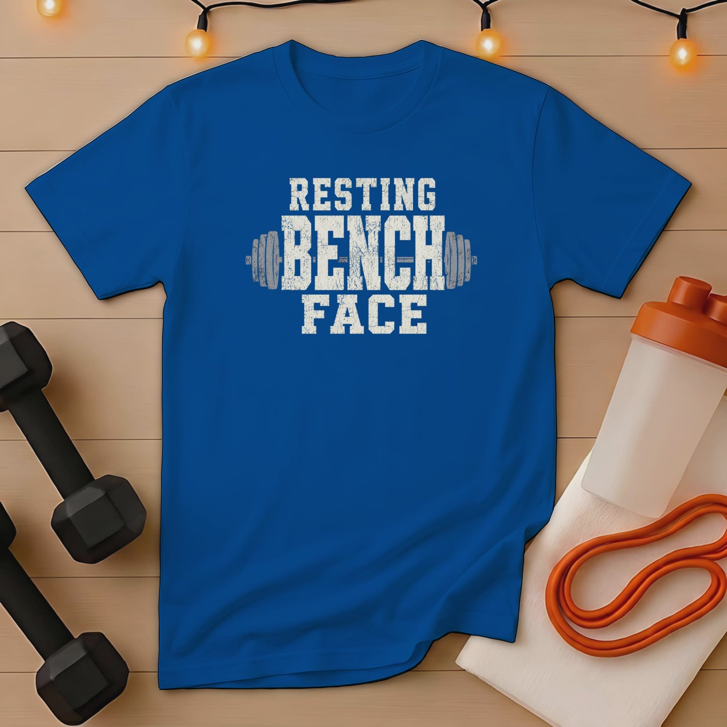 Blue t-shirt with white distressed text "RESTING BENCH FACE" and barbell graphic.