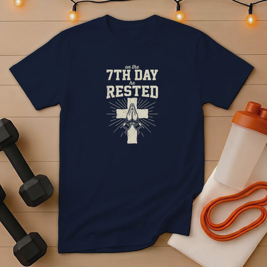 Navy t-shirt with "on the 7th day he rested" and praying hands cross design.