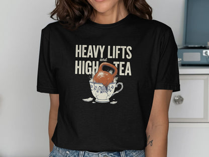 Black t-shirt with text "HEAVY LIFTS and HIGH TEA" over a kettlebell in a broken teacup.