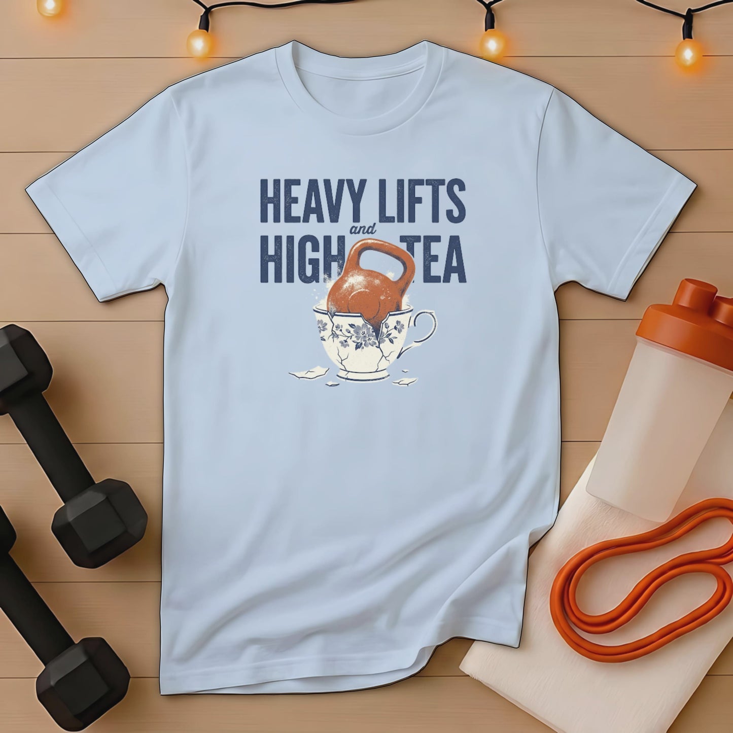 Light blue t-shirt with kettlebell in teacup and text "Heavy Lifts and High Tea".