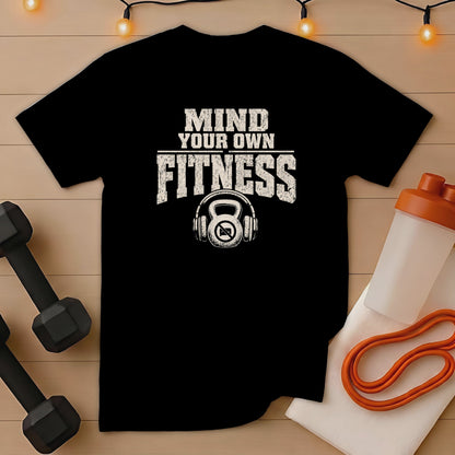 Black t-shirt with "Mind Your Own Fitness" text and kettlebell headphones graphic.