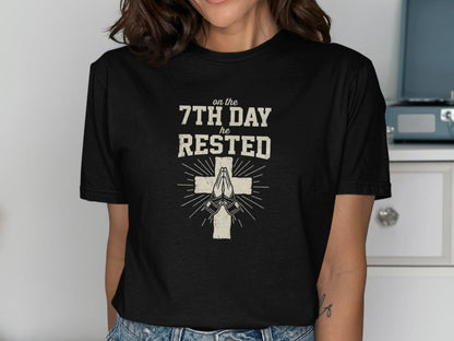 Black t-shirt with "on the 7th DAY HE RESTED" and praying hands with cross.