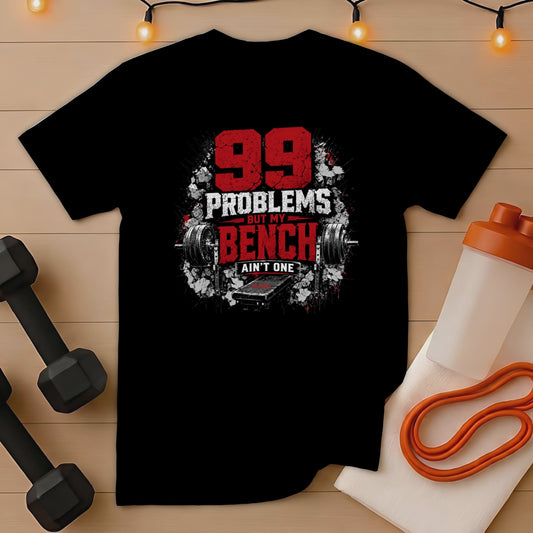 Black t-shirt with text "99 Problems But My Bench Ain't One" and barbell graphic.