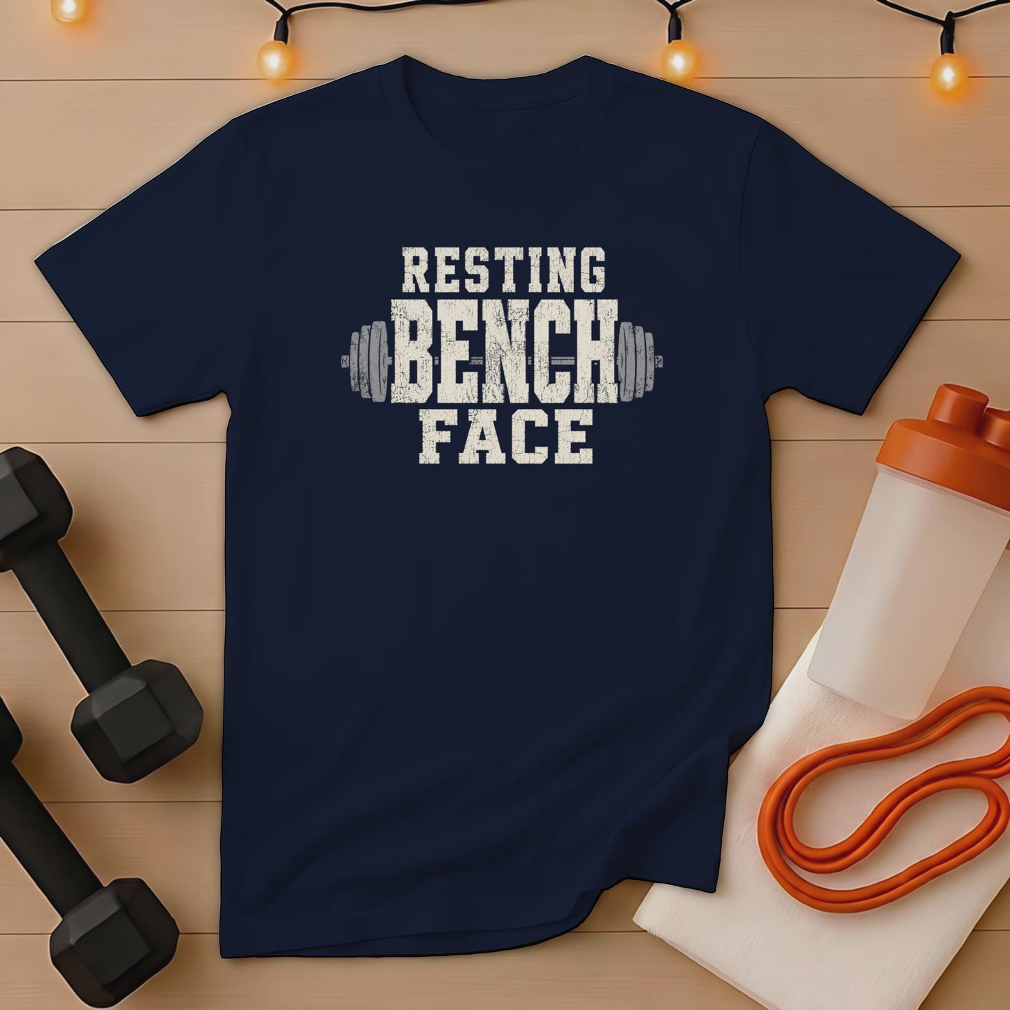 Navy t-shirt with distressed white text reading "RESTING BENCH FACE" and dumbbell graphics.
