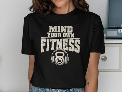 Black t-shirt with "Mind Your Own Fitness" text and kettlebell with headphones graphic.