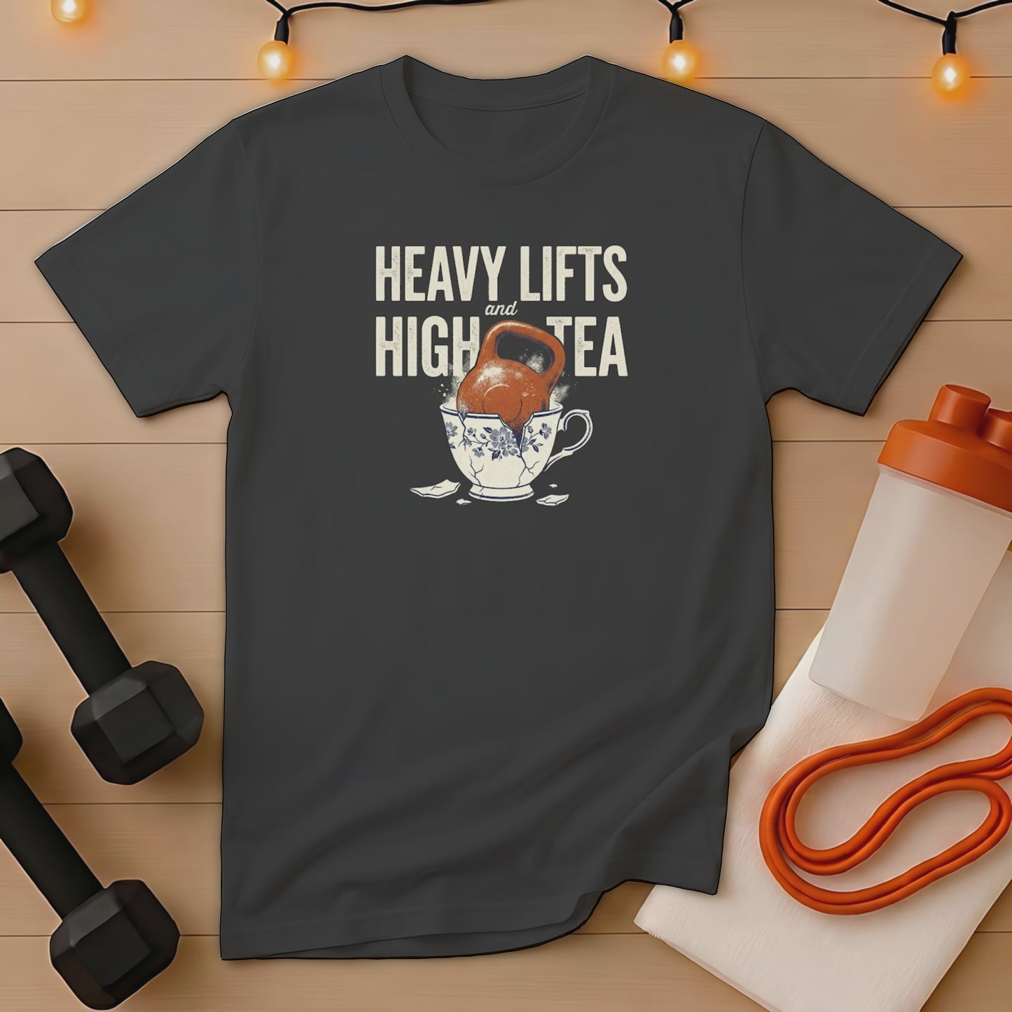Dark grey t-shirt with "Heavy Lifts and High Tea" and a teacup spilling kettlebells.