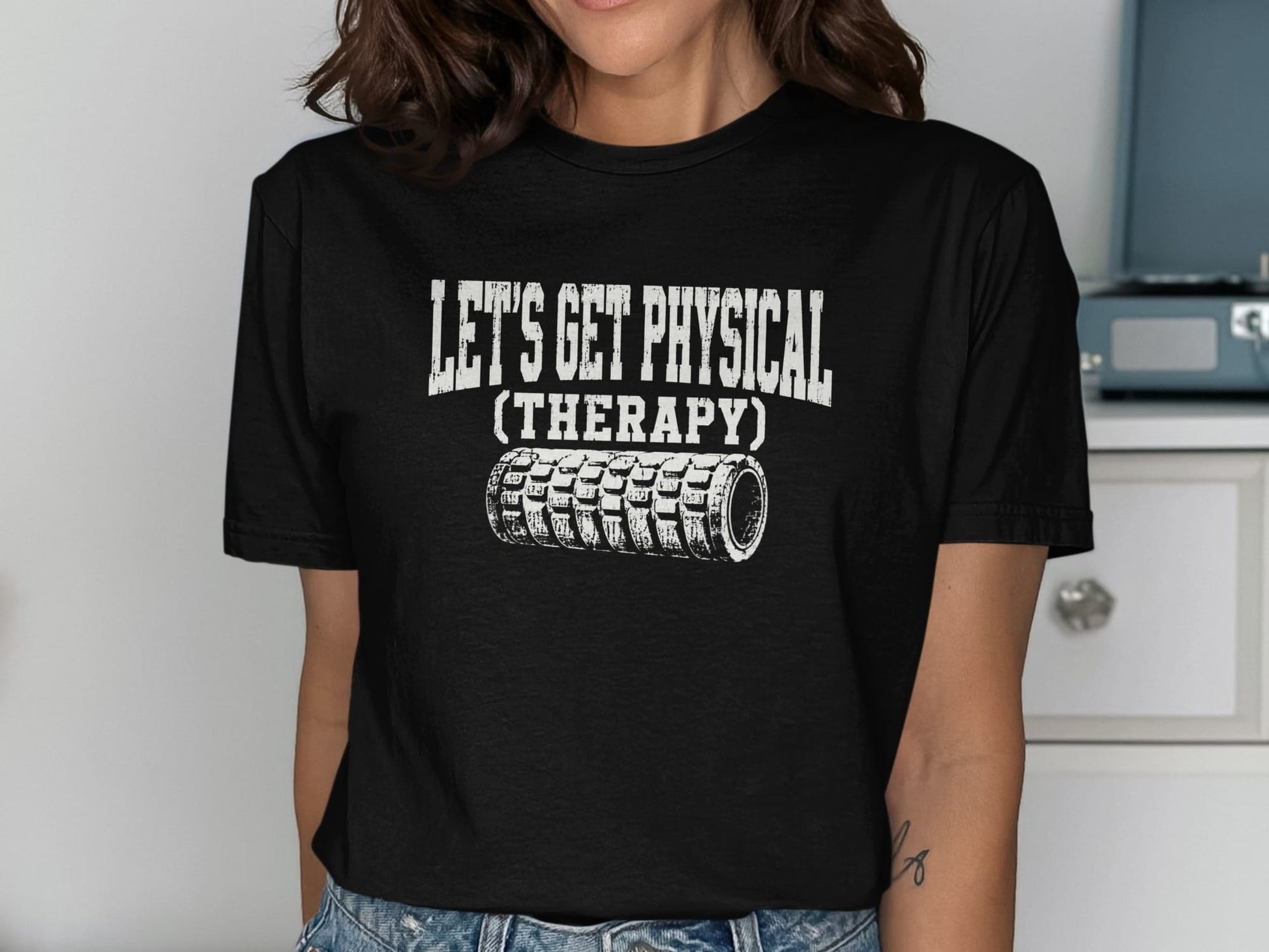Black t-shirt with white text "LET'S GET PHYSICAL (THERAPY)" and foam roller graphic.