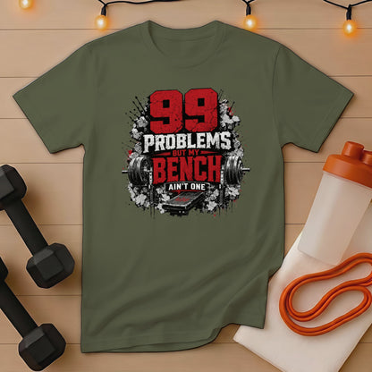 Olive green t-shirt with "99 PROBLEMS BUT MY BENCH AIN'T ONE" text and barbell graphic.
